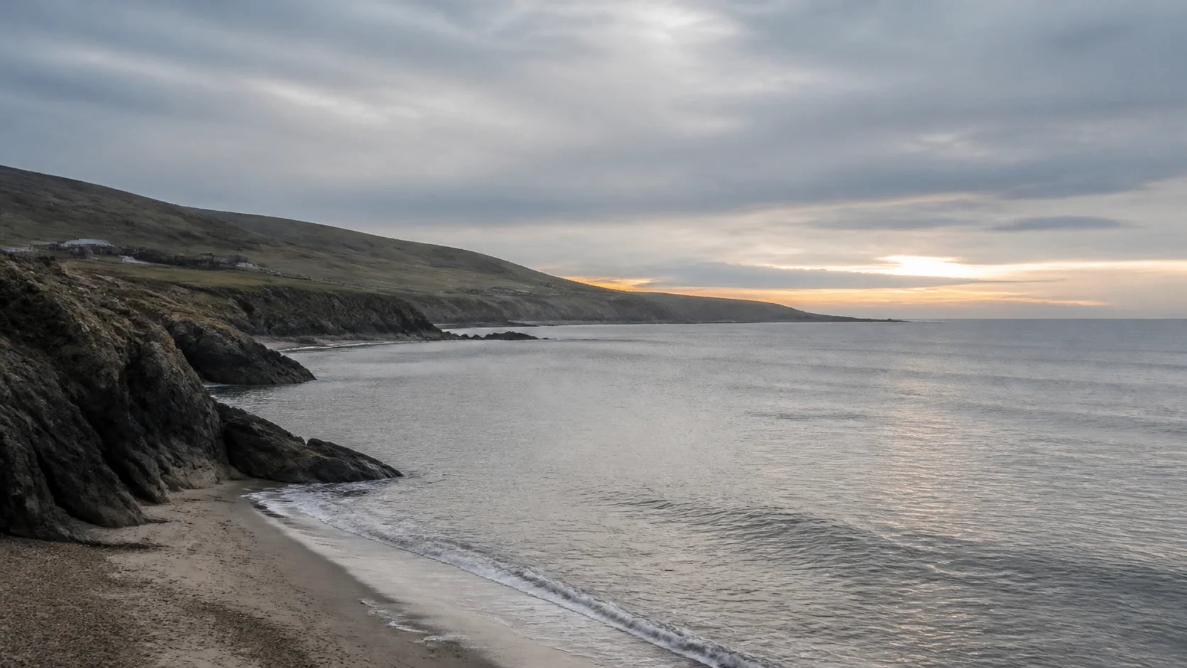 A muted coastline under a layered gray dawn sky